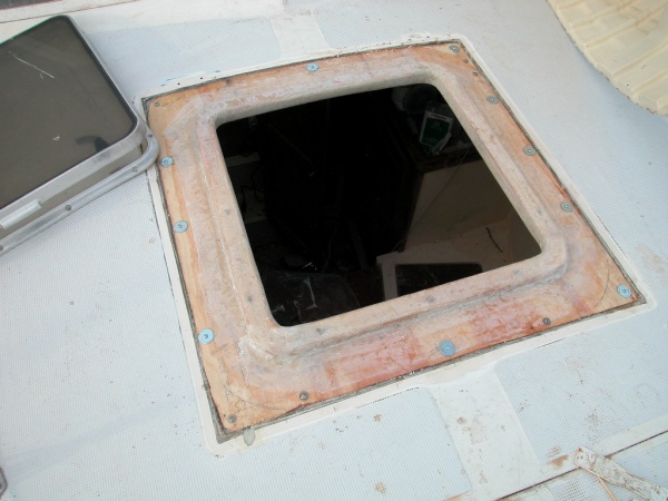 The old wood framed hatch has been cut away with a Sawsall. The deck is cut at a 30 degree angle to allow the new hatch to be scarfed in. It has been set in epoxy and bolted until the epoxy is cured.